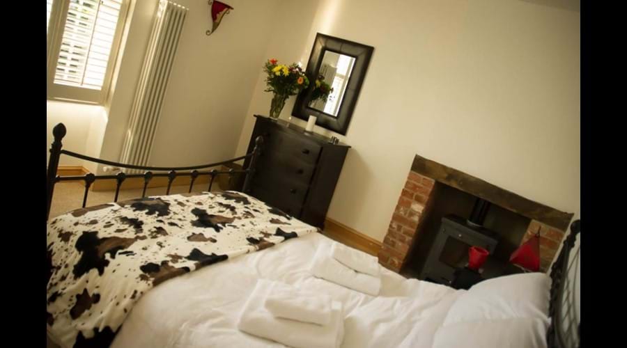 Double bedroom with wrought iron bedstead, wood burner and solid oak furnishings