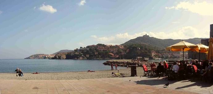 Collioure - strandrestaurants en aan de overkant van de baai. Zonnen en nog bruisende in november. Ontspan in de zon met een drankje of een maaltijd en kijken naar de wereld.