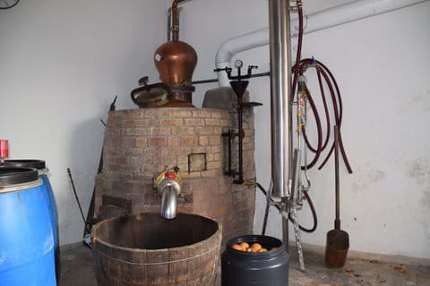 Gemauerte Destille mit währender Maische (links im blauen Faß) und Äpfeln