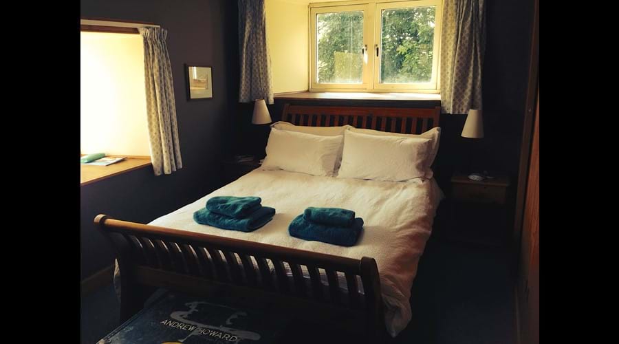 Master bedroom with window above mill wheel and window looking out over the garden, the swing and Loch Fada in distance