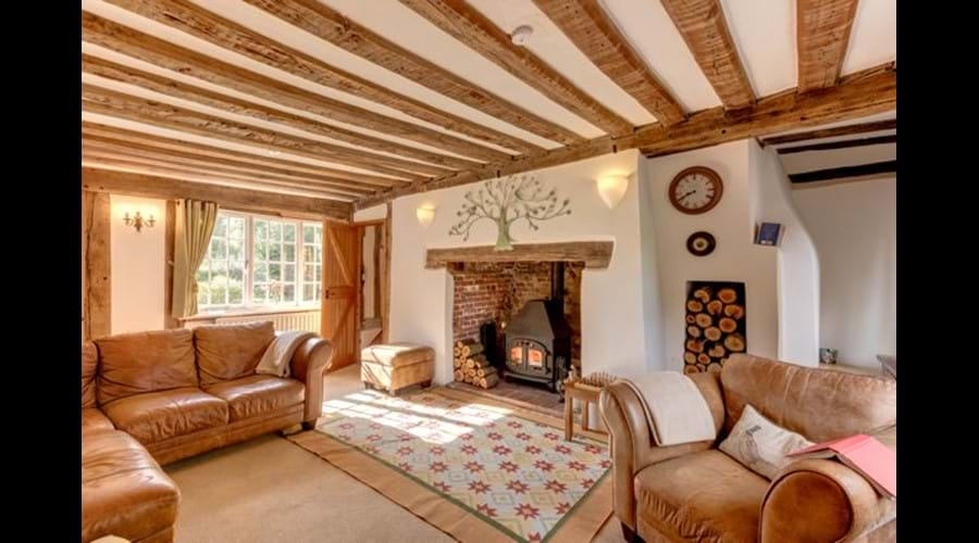 The beamed sitting room, with a log burner in the inglenook fireplace.