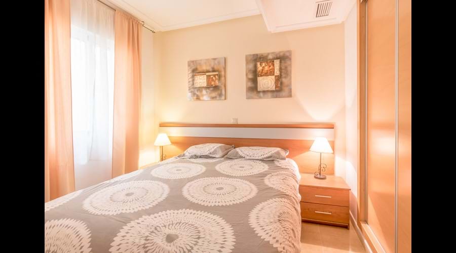 2nd bedroom with large fitted wardrobe & storage chests, bedside lockers and full-length mirror