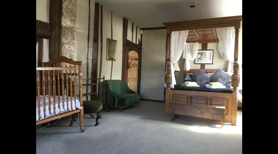 Setting in master bedroom of four poster and cot