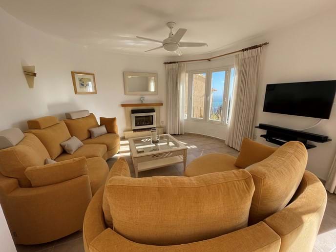 Lounge with double sofas, TV, fireplace and picture windows with sea views