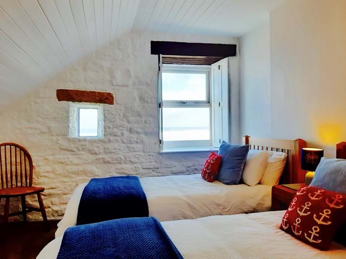 The second bedroom has comfortable twin oak beds furnished with quality linen, and a spectacular sea view