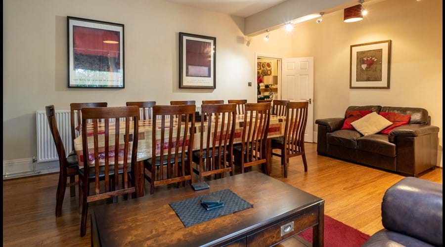 Lower ground floor dining room with hardwood table seating up to 12 people, 2 sofas and coffee table.