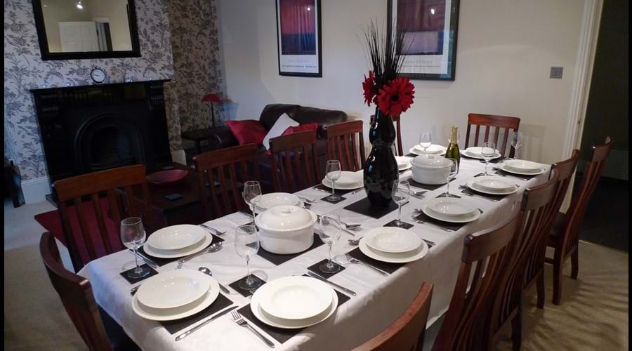 Dining table with large hardwood table and chairs seating up to 12 people and separate seating area with 2 leather sofas and coffee table
