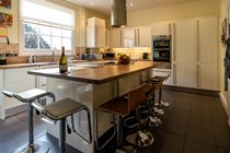 Kitchen with large island, barstools, electric hob, double oven, 2 fridge freezers, washing maching and dryer