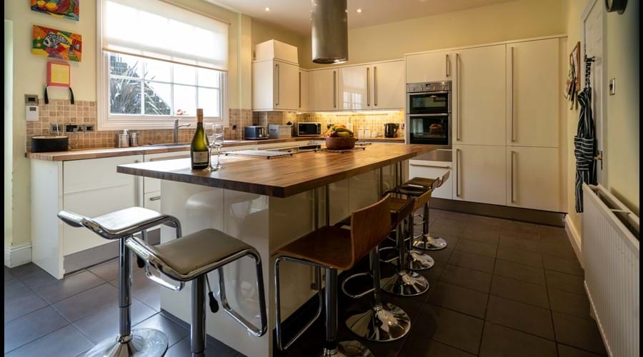 Kitchen with large island, barstools, electric hob, double oven, 2 fridge freezers, washing maching and dryer