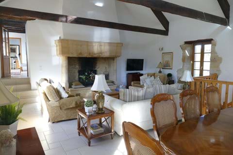 A view of the lovely sitting room in Le Chataignier with exposed beams and large stone fireplace