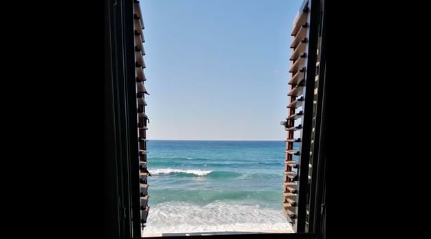 Blue sea and white waves through wooden shutters