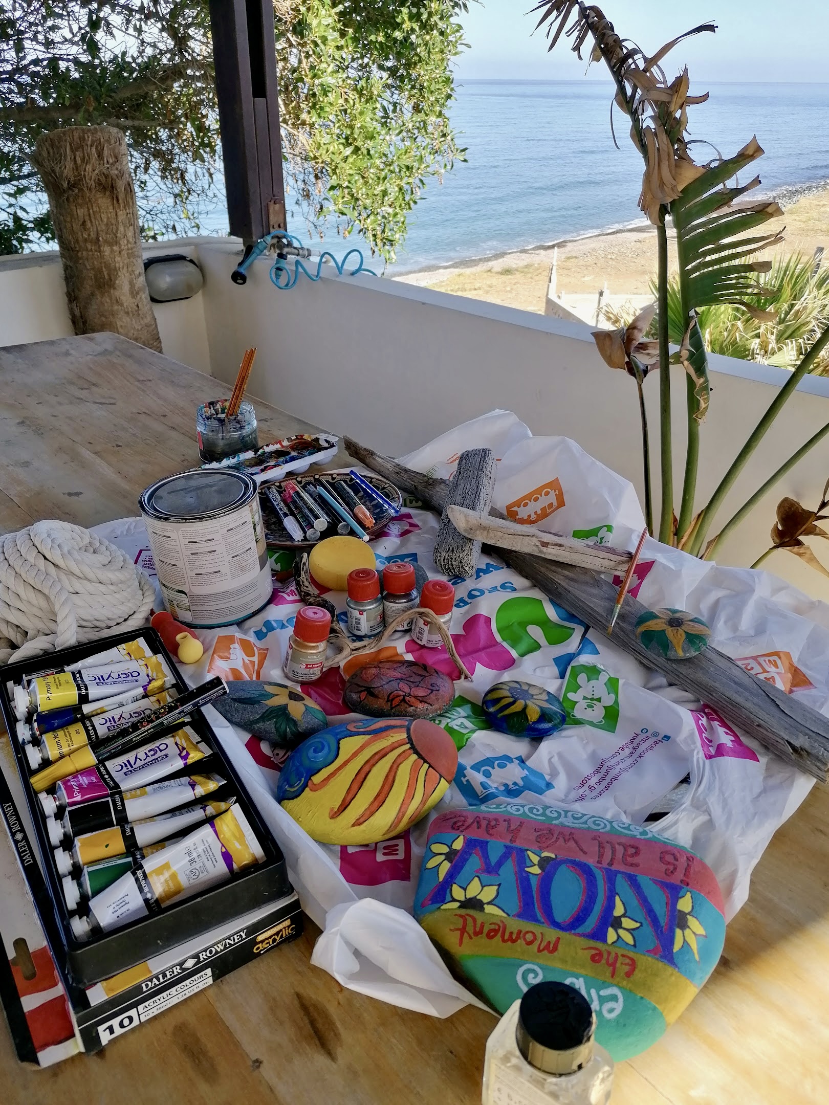 Paints and pebbles on a table by the sea