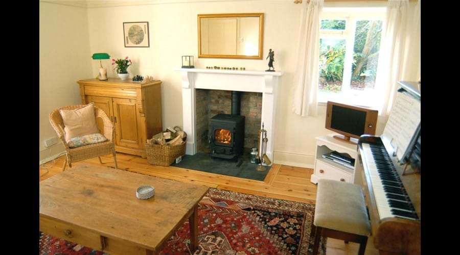 Family room with wood burner, piano, games cupboard. And now with a much bigger TV than the one shown in the picture!