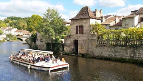 An open topped tourist boat full of tourists on the river at Brantome