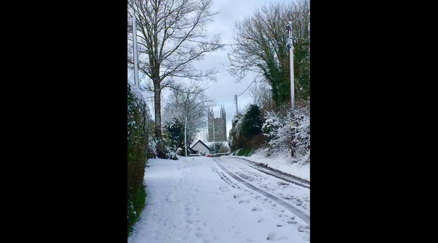 A snowy view up the private lane towards the church in Week St Mary