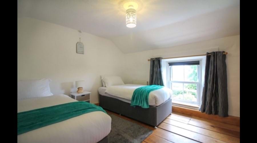 Twin bedroom with wooden floors and soft slate grey rug