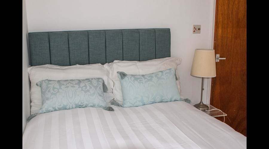 Smaller top floor back bedroom. Small double bed, comfortable size for a single adult. Hooks and chest of drawers rather than wardrobe and a TV to keep you entertained.