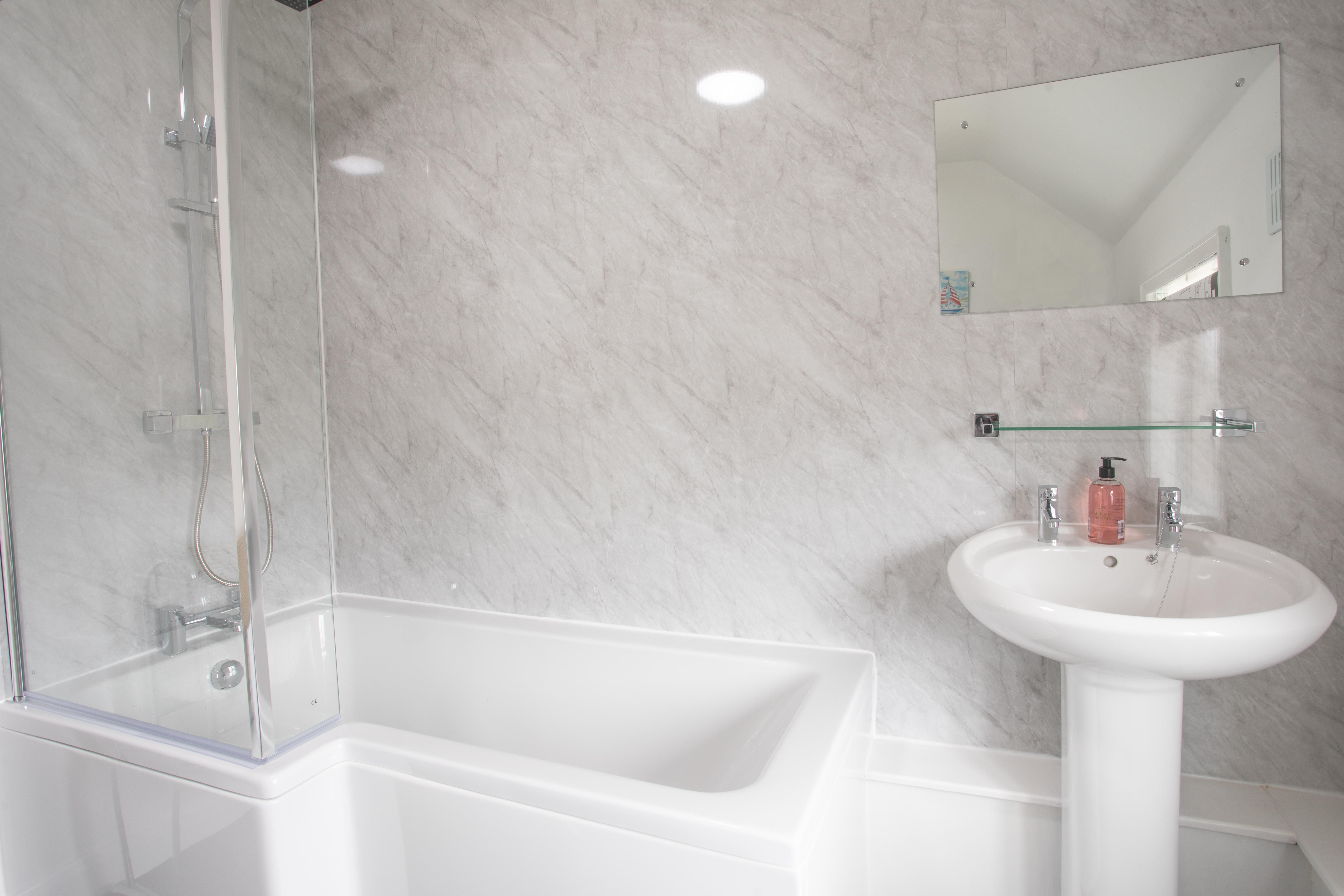 The bathroom has a shower over the bath.