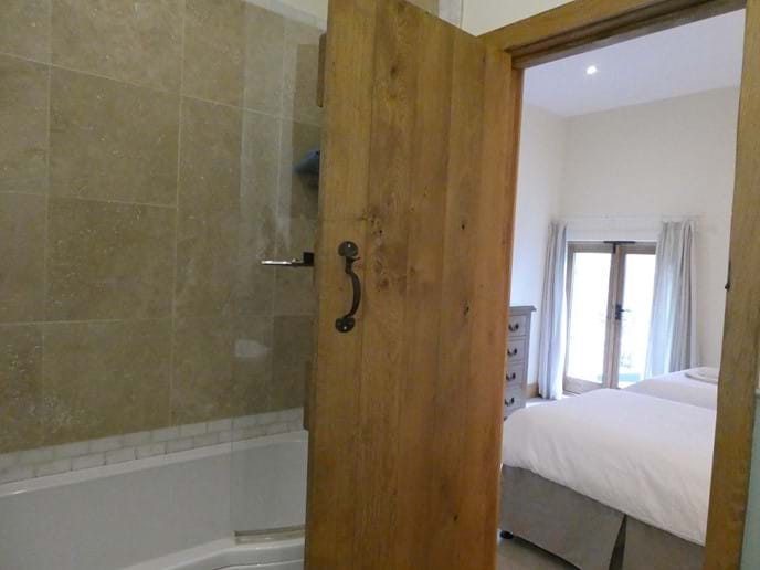 En-suite bathroom to twin room with full size bath and overhead shower