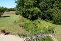 View from the bedroom window, looking down to the wooden bridge under which the millstream flows