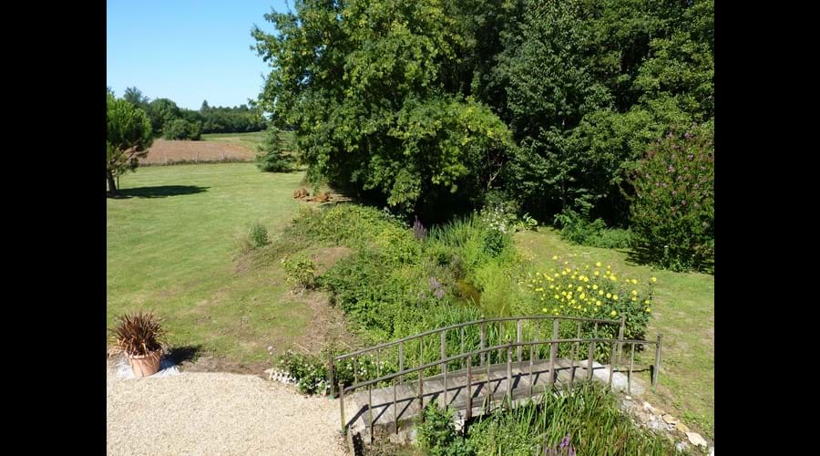 View from the bedroom window, looking down to the wooden bridge under which the millstream flows