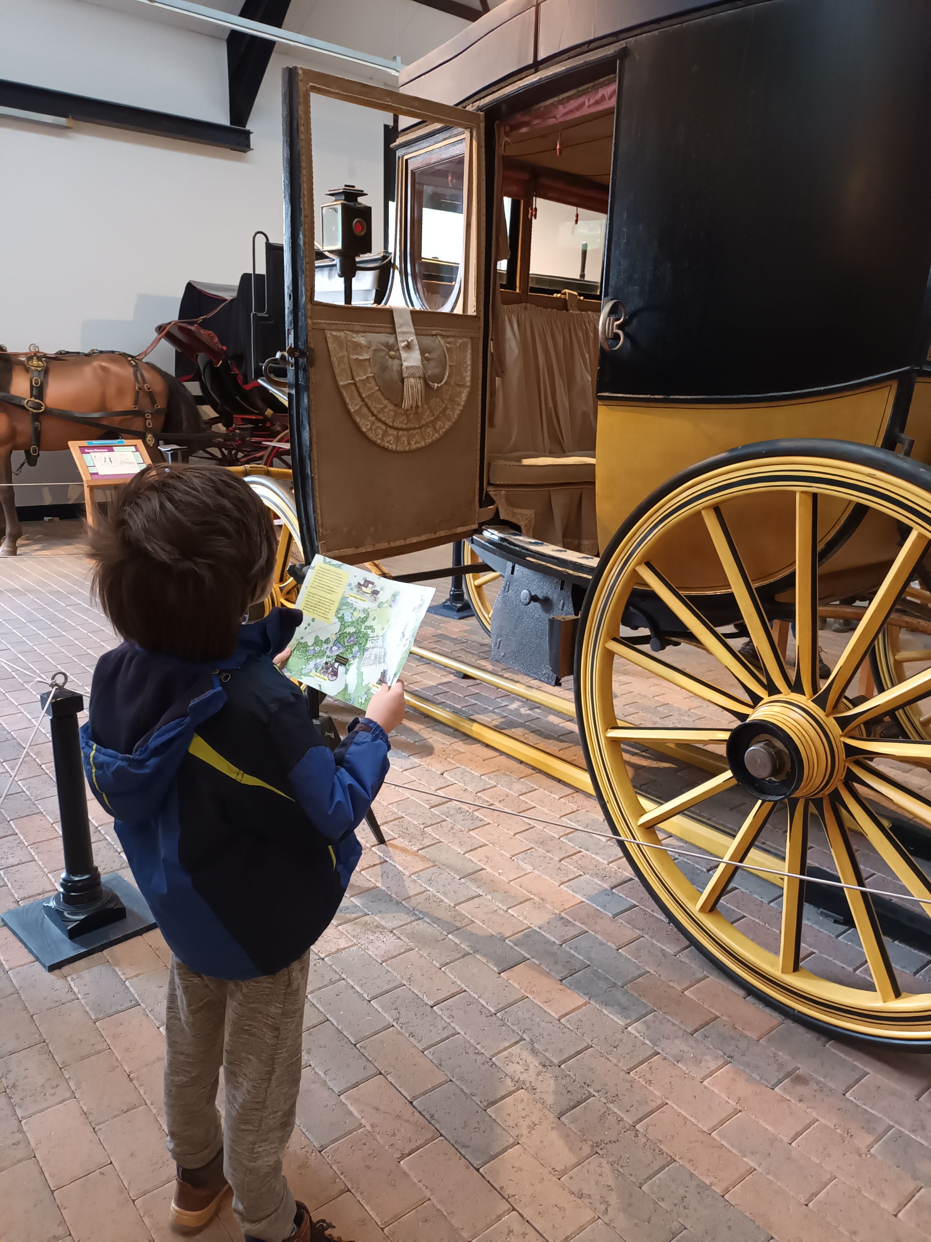A boy reading an information leaflet stood in front of a carriage