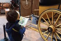 A boy reading an information leaflet stood in front of a carriage