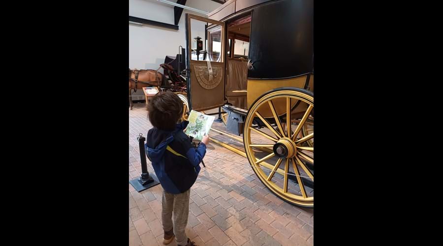 A boy reading an information leaflet stood in front of a carriage