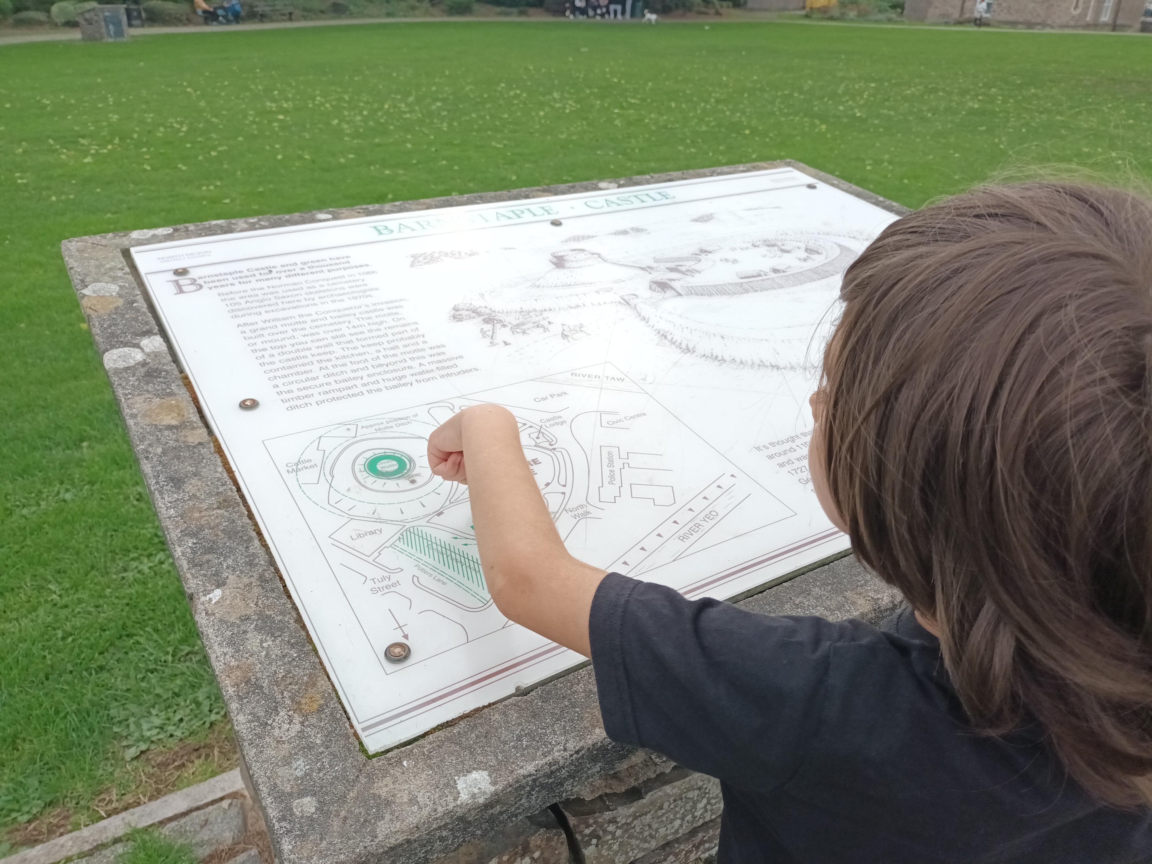 a boy points to the information display for Barnstaple Castle