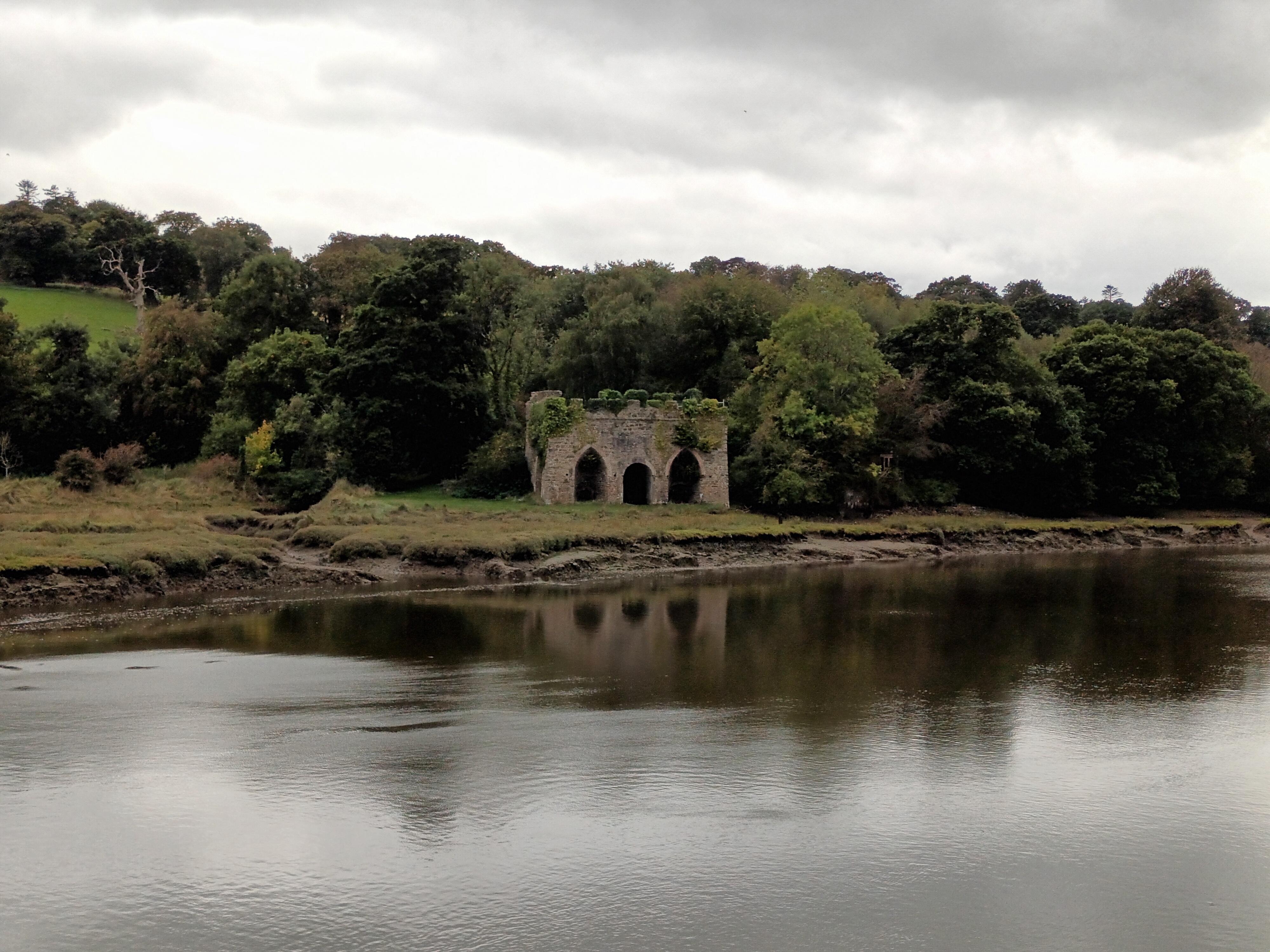 A ruin sitting amongst trees, next to the River.