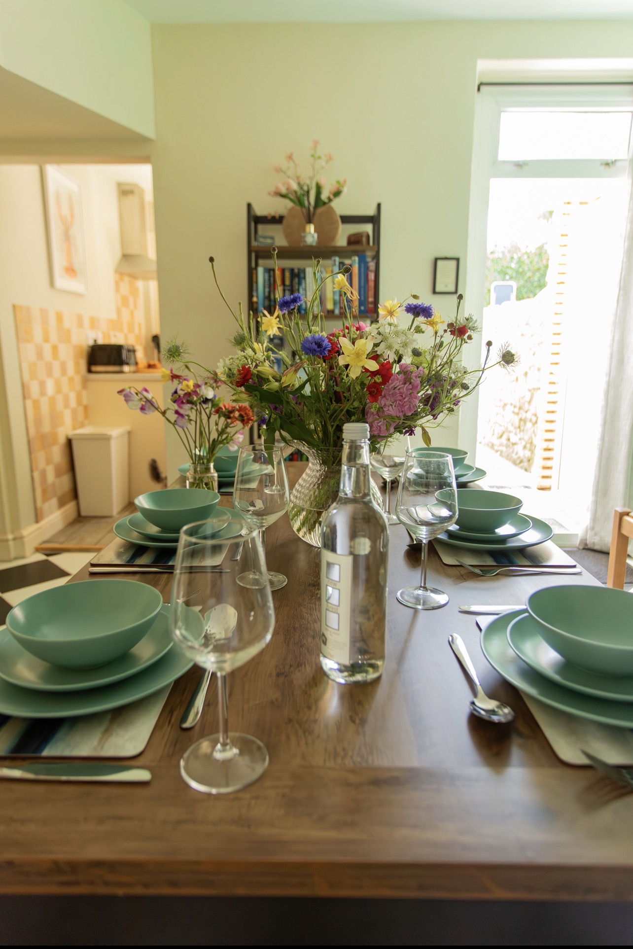 Dining room with wooden table laid for guests, chairs and decorative fireplace