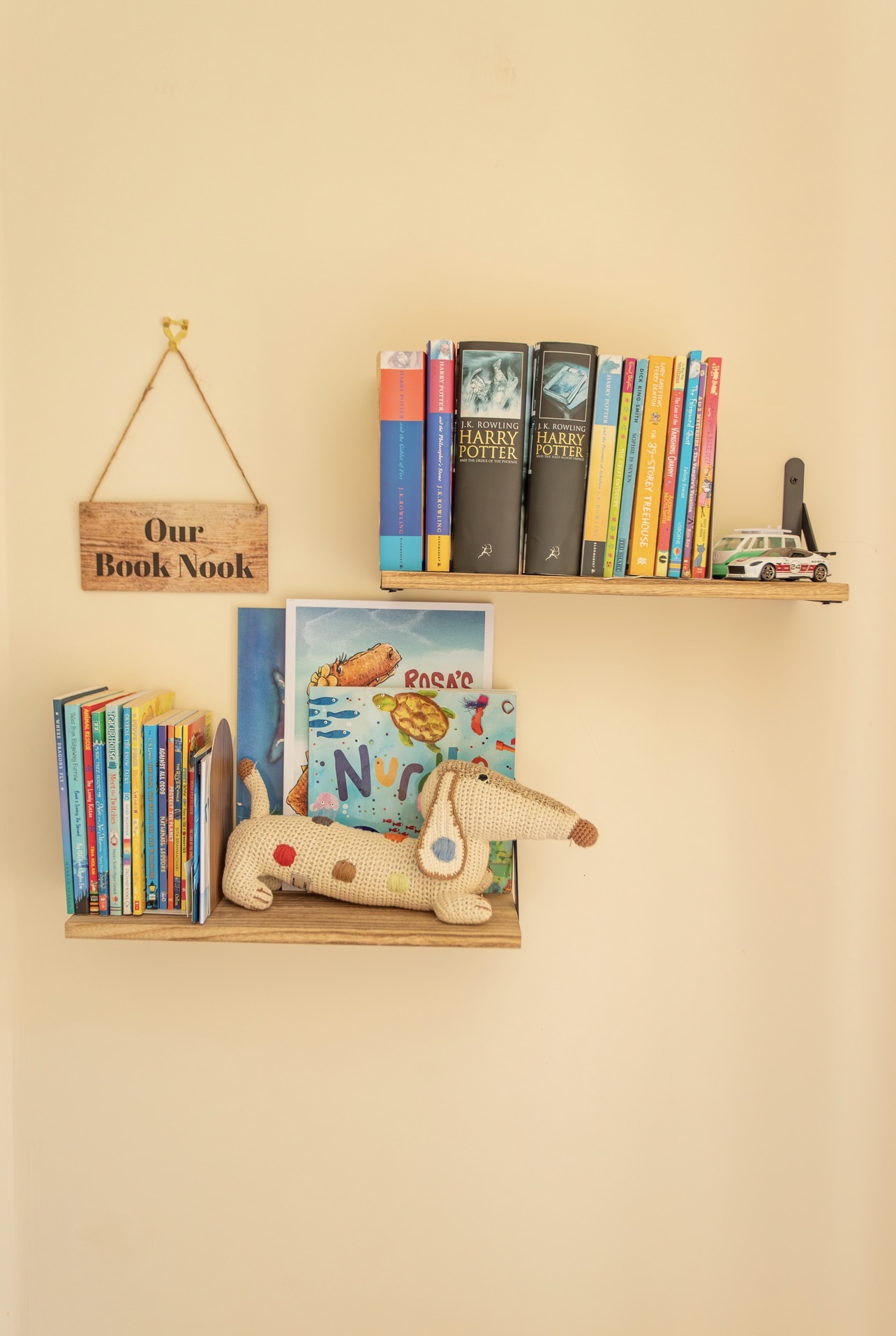 Small bookshelf in the twin bedroom with children’s books and decorative sign reading book nook