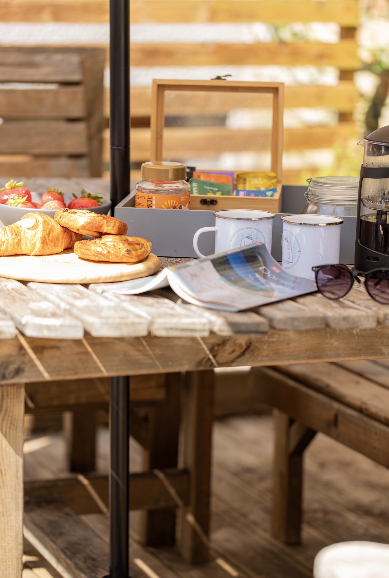 Outdoor wooden dining table in the cottage garden set with coffee, pastries and breakfast items