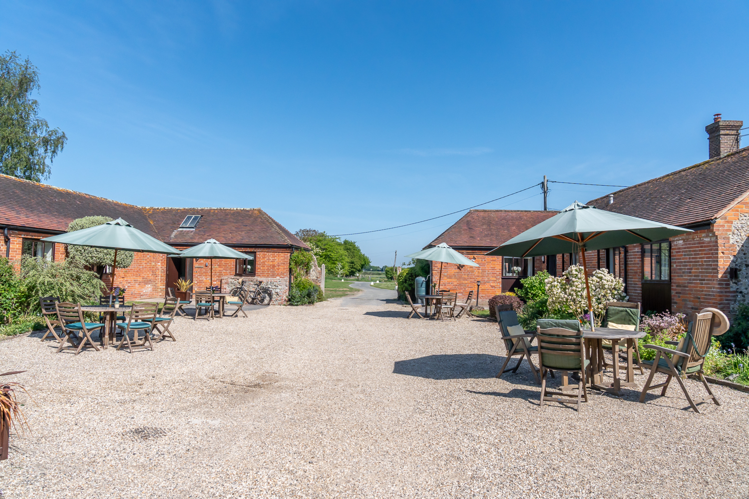 Shared courtyard at Canute Cottages in Cobnor Estate, Chidham, West Sussex, featuring outdoor tables, seating, and landscaped communal space