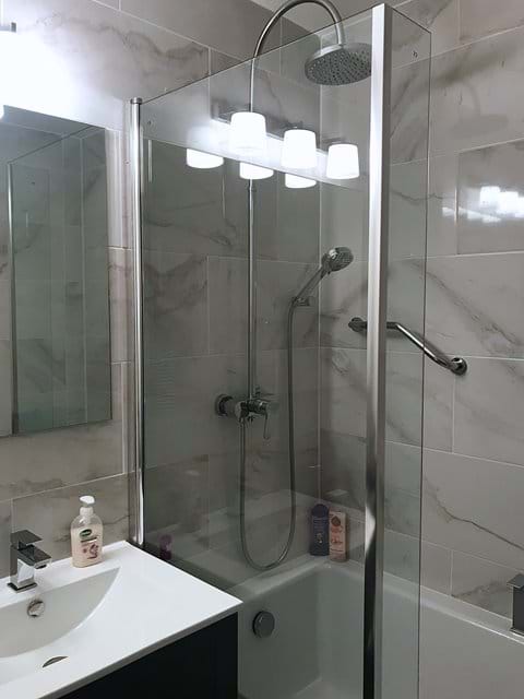 Bathroom has L shaped bath with roomy over bath shower cubicle.